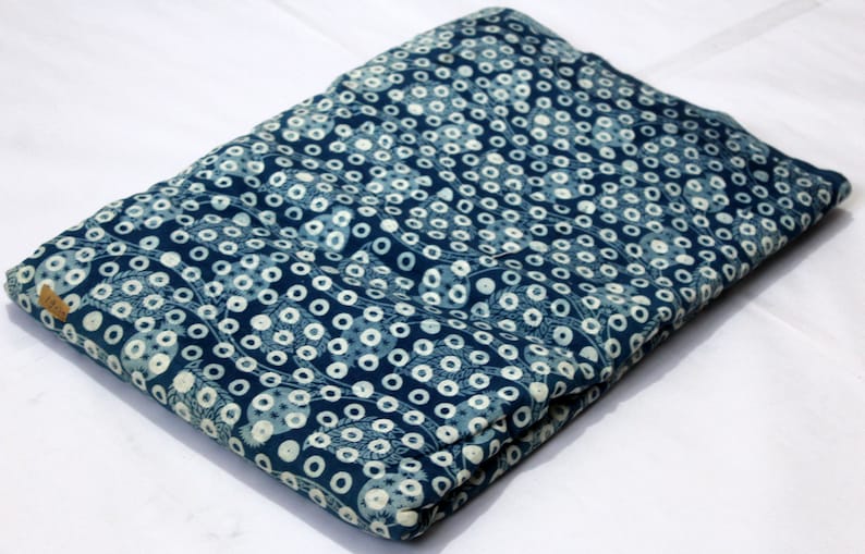 May include: A folded blue fabric with a white polka dot pattern. The fabric has a subtle floral design.