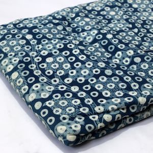 May include: Blue fabric with a white pattern of circles and leaves. The fabric is folded in half.