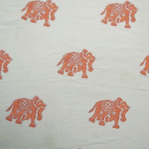 May include: White fabric with a repeating pattern of orange elephants. The elephants are stylized and have intricate designs on their bodies.