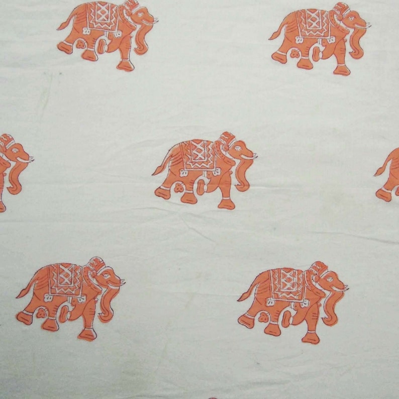 May include: White fabric with a repeating pattern of orange elephants. The elephants are stylized and have intricate designs on their bodies.