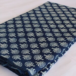 May include: A folded piece of indigo blue fabric with a white floral pattern. The fabric is folded in half and the pattern is visible on both sides.