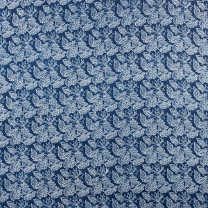 May include: A blue fabric with a white floral pattern. The pattern is a repeating design of leaves and flowers.