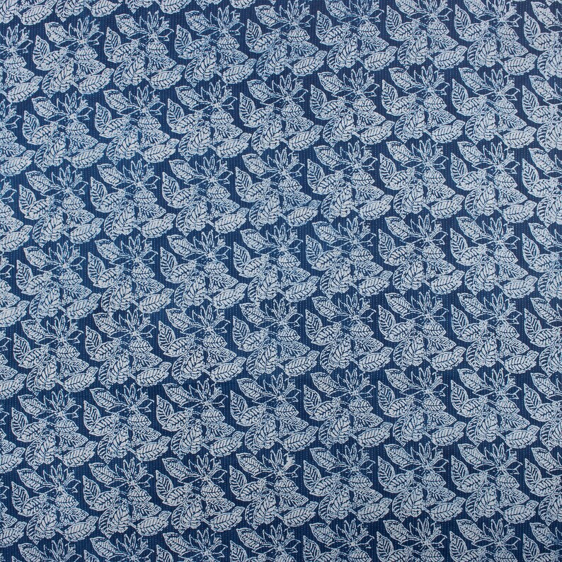 May include: A blue fabric with a white floral pattern. The pattern is a repeating design of leaves and flowers.