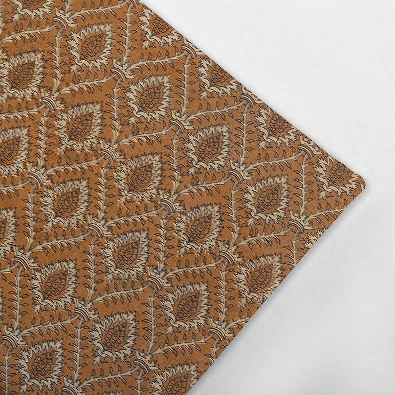May include: A brown fabric with a repeating pattern of white and black floral designs. The fabric has a subtle sheen and a soft texture.
