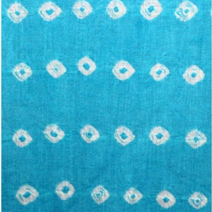 May include: A turquoise blue fabric with a white shibori tie-dye pattern. The pattern is made up of small, white circles.
