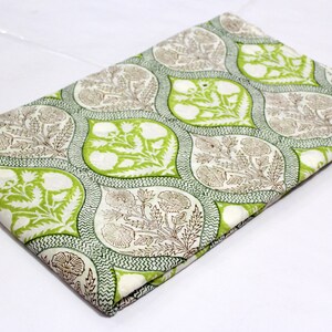 May include: White cotton fabric with a green and brown floral print. The print features a repeating pattern of teardrop shapes with intricate floral designs.