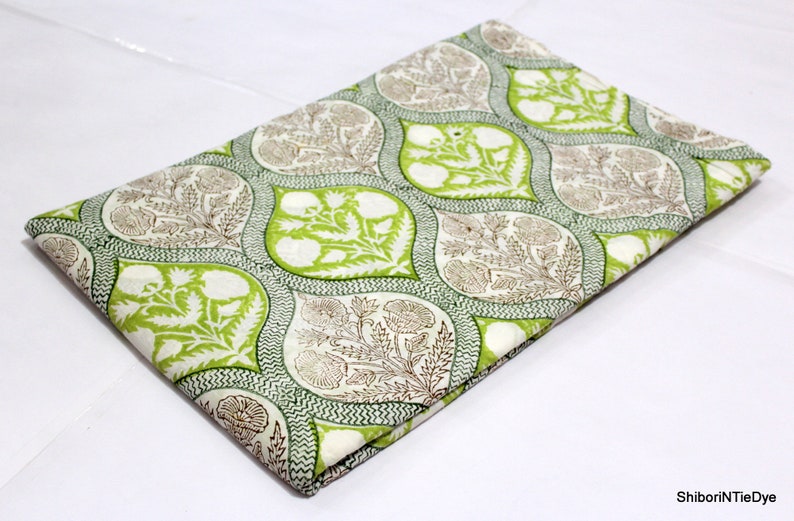 May include: White cotton fabric with a green and brown floral print. The print features a repeating pattern of teardrop shapes with intricate floral designs.