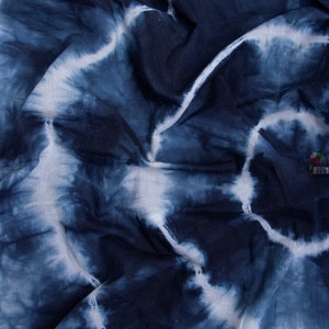 May include: A close-up of a blue and white tie-dye fabric. The fabric is wrinkled and has a soft, textured feel.