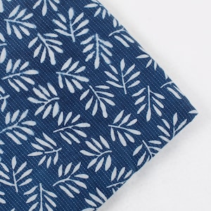 May include: A close-up of a blue fabric with a white leaf pattern. The fabric has a subtle texture and is perfect for quilting or other craft projects.