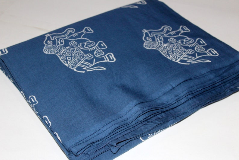 May include: A folded stack of blue fabric with a white elephant print. The fabric is folded neatly and has a smooth texture.