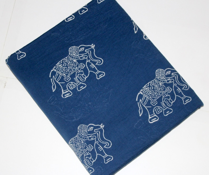 May include: A blue cotton fabric with a white elephant print. The elephants are in a traditional Indian style with intricate details. The fabric is perfect for crafting projects, quilting, or making clothing.