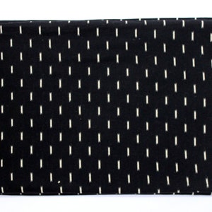 May include: Black fabric with a white ikat pattern. The fabric has a white border.