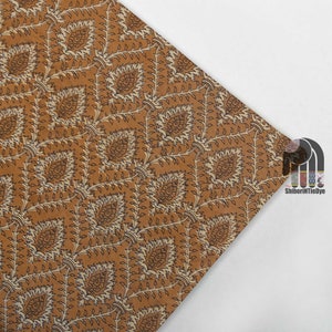 May include: A brown fabric with a white and brown floral pattern. The fabric has a subtle sheen and a soft texture.