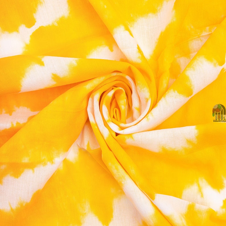 May include: Yellow and white tie-dye fabric with a swirl pattern.