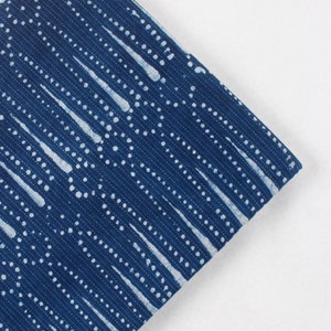 May include: Blue fabric with a white pattern of dots and lines. The fabric has a textured surface.