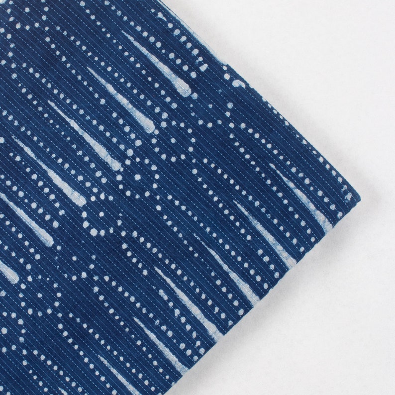 May include: Blue fabric with a white pattern of dots and lines. The fabric has a textured surface.