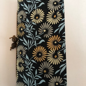 May include: A black fabric envelope with a floral pattern in shades of blue, yellow, and brown. The envelope has a brown leather strap with a decorative metal clasp.