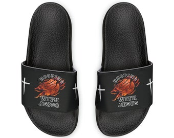 May include: A pair of black slides with a white cross on each side. The slides have a graphic of a basketball on fire with the text "HOOPING WITH JESUS".