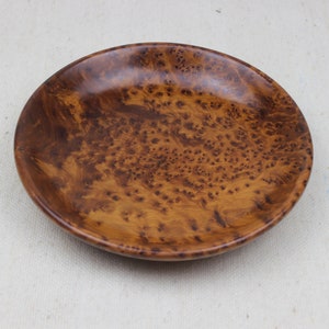 Può includere: Una ciotola di legno rotonda con un motivo a venature di legno marrone e arancio.