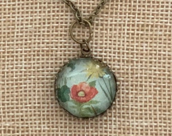 Vintage style necklace with illustration of a red poppy and wildflowers set in circle glass dome and bronze crown edge tray w/ chain