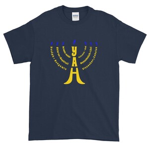 May include: A navy blue t-shirt with a yellow menorah design. The menorah is surrounded by the names of the 12 tribes of Israel in blue text.