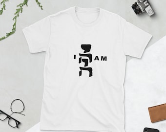 May include: White t-shirt with a black graphic design featuring a stylized figure and the text "I AM".