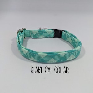 May include: A turquoise and white patterned cat collar with a silver buckle and black adjustable slider. "BLAKE CAT COLLAR" is printed below the collar.