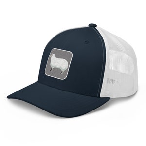 May include: A navy blue and white trucker hat with a white sheep graphic on the front. The sheep is in a grey square with a wavy pattern.