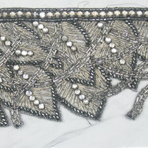 May include: Silver and black beaded trim with a leaf design. The trim has a scalloped edge and is perfect for adding a touch of elegance to any project.