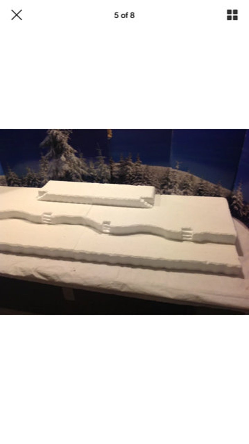 May include: A white, three-tiered, foam display platform with a snowy, wintery theme. The platform has a textured surface and is designed for displaying products or crafts.