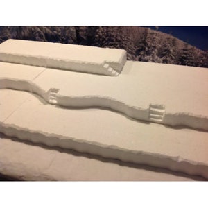 May include: A white foam terrain model with three levels and three sets of stairs. The model is designed for tabletop gaming.