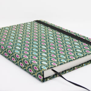 Può includere: Un diario verde con una copertina a motivi dorati e rosa e una chiusura elastica nera.