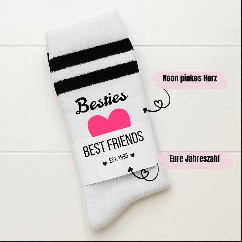 Puede incluir: Calcetines blancos con rayas negras en la parte superior. Los calcetines tienen la palabra "Besties" encima de un coraz&oacute;n rosa, y las palabras "BEST FRIENDS EST. 1995" est&aacute;n impresas en una banda blanca.