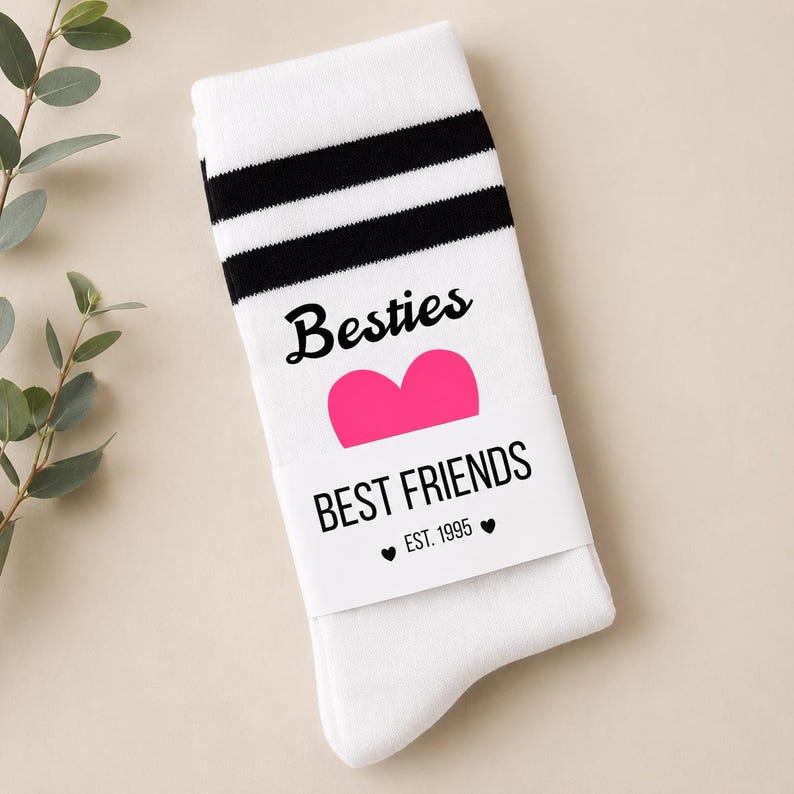 Puede incluir: Calcetines blancos con rayas negras en la parte superior. Los calcetines tienen la palabra "Besties" encima de un coraz&oacute;n rosa, y "BEST FRIENDS" con "EST. 1995" debajo. Un gran regalo para una mejor amiga.