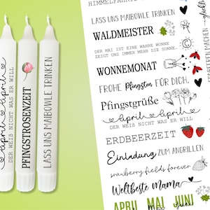 Könnte beinhalten: Drei weiße Kerzen mit schwarzem Text und Illustrationen. Die Kerzen sind beschriftet mit "April", "Pfingstrosenzeit" und "Lass uns Maibowle trinken".