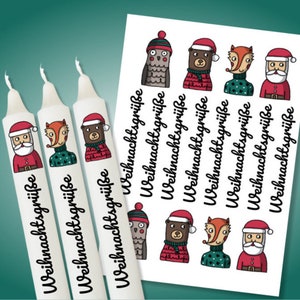 Può includere: Tre candele bianche con illustrazioni a fumetti di Babbo Natale, una volpe e un orso con cappelli e maglioni natalizi. Il testo "Weihnachtsgrüße" è stampato sulle candele. È visibile anche un foglio di adesivi con le stesse illustrazioni.