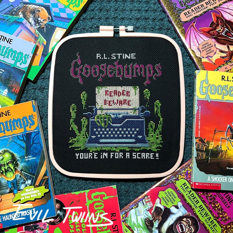 May include: A black cross-stitch featuring the text "R.L. Stine Goosebumps" and a typewriter with "Reader Beware" on the paper. Green and pink accents are used. Surrounded by Goosebumps books.
