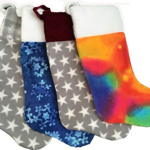 May include: Four Christmas stockings with different patterns. One stocking is grey with white stars, one is blue with white snowflakes, one is grey with white stars and a red cuff, and one is orange, blue, and green with a white cuff.