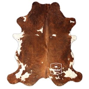 以下が含まれることがあります： 自然な茶色と白の模様の牛革ラグ。ラグは不規則な形状で、柔らかい質感です。このラグは、家やオフィスでの床材や装飾的なアクセントとして使用するのに適しています。