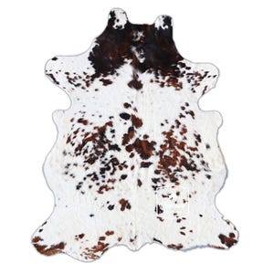 以下が含まれることがあります： 白地に茶色と黒の斑点のある牛革の敷物。敷物は約1.5メートル×2.1メートルです。