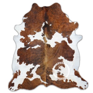 Puede incluir: Alfombra de piel de vaca marrón y blanca con un patrón marrón y blanco. La alfombra tiene un aspecto y una sensación naturales y rústicos. Es una gran adición a cualquier decoración del hogar.