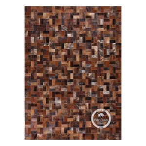 May include: A brown and tan patchwork cowhide rug with a geometric pattern. The rug is made of individual pieces of leather that have been sewn together to create a unique design. The rug is perfect for adding a touch of rustic charm to any room.