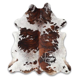以下が含まれることがあります： 茶色と白の斑点模様の天然模様の牛革ラグ。 ラグは不規則な形状で、柔らかい質感で、インテリアに適しています。 「PrimeLand Cowhides」というロゴが表示されています。