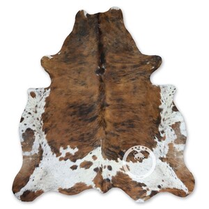 以下が含まれることがあります： 茶色と白の牛革の敷物で、自然な斑点模様があります。敷物は本物の牛革で作られており、柔らかく高級感のある肌触りです。