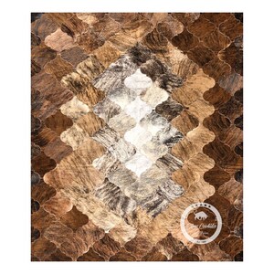 May include: A brown, black, and white cowhide rug with a geometric pattern. The rug is made of individual pieces of cowhide that have been sewn together to create a unique design.