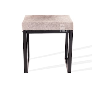 May include: A black metal stool with a grey cowhide seat. The stool is 46 cm tall and has a square seat.