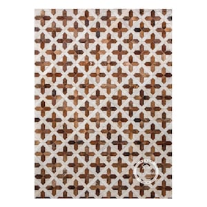 Puede incluir: Una alfombra geométrica de color marrón y blanco hecha de cuero. La alfombra tiene un patrón repetido de cruces.