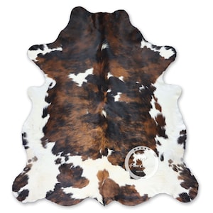 May include: A brown, black, and white cowhide rug with a natural, irregular shape. The rug is made of real cowhide and has a soft, luxurious feel.