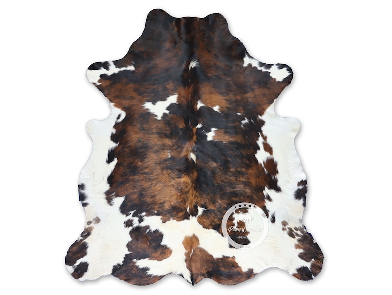May include: A brown, black, and white cowhide rug with a natural, irregular shape. The rug is made of real cowhide and has a soft, luxurious feel.