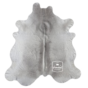 以下が含まれることがあります： 中央に白い「Primelend Cowhides」ロゴが入ったグレーの牛革敷物です。